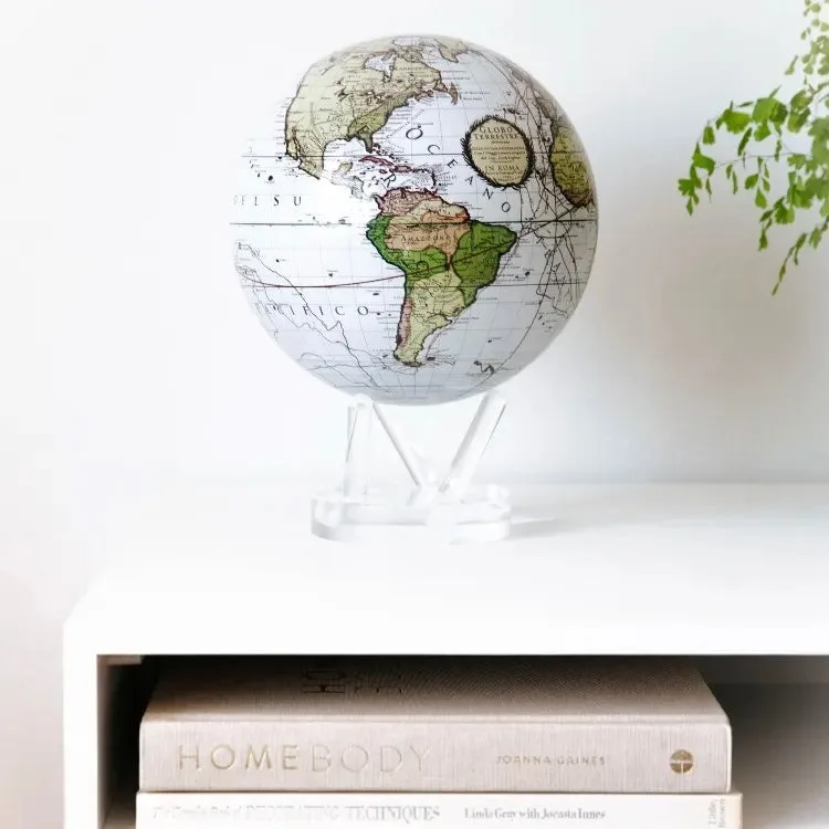 Globe Mova Antique Cassini blanc sur un meuble blanc avec des livres