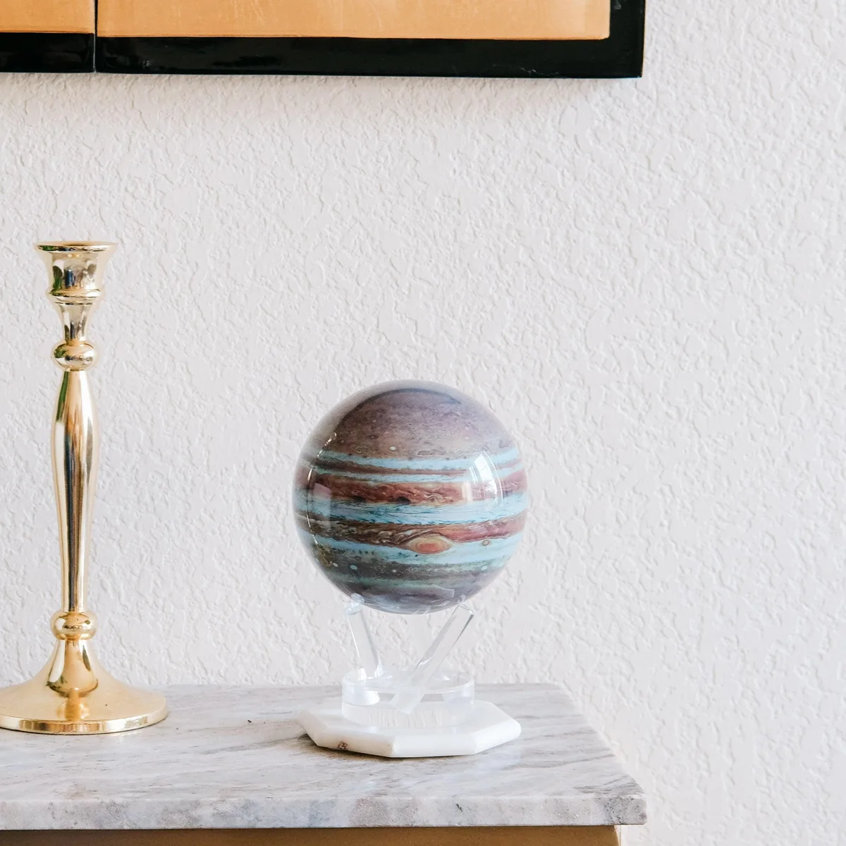 Globe Mova Jupiter sur un meuble clair près d'un chandelier doré